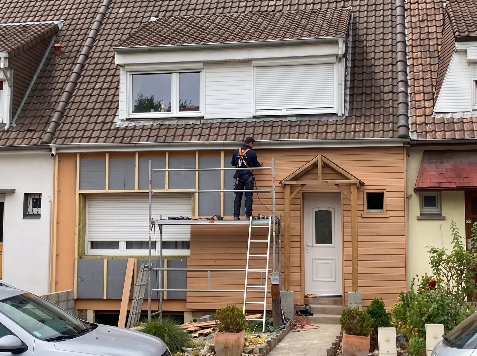 Illustration : artisan en bardage isolant sur façade de maison, pose de revêtement bois avec isolation thermique